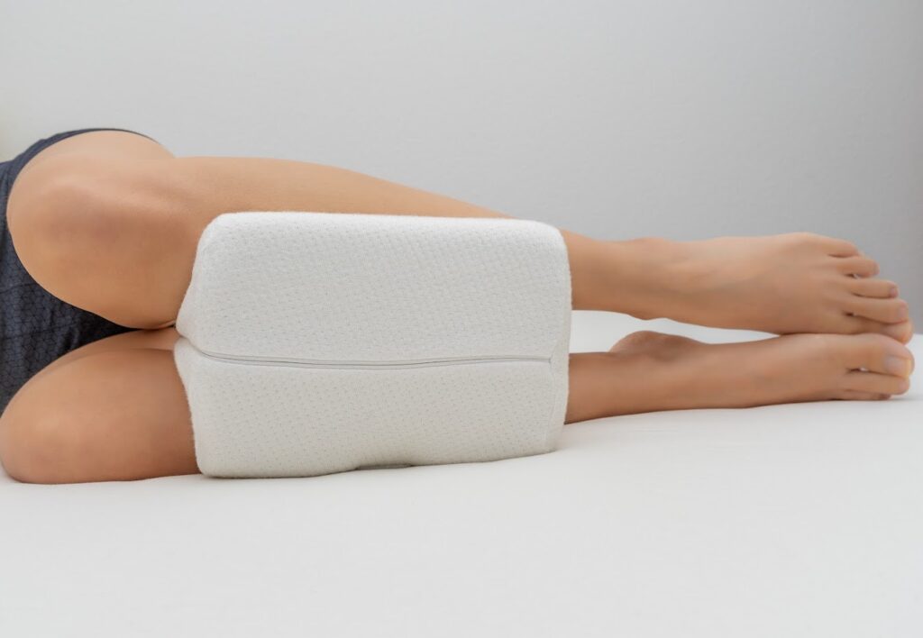 A person lying on their side with a pillow between their legs